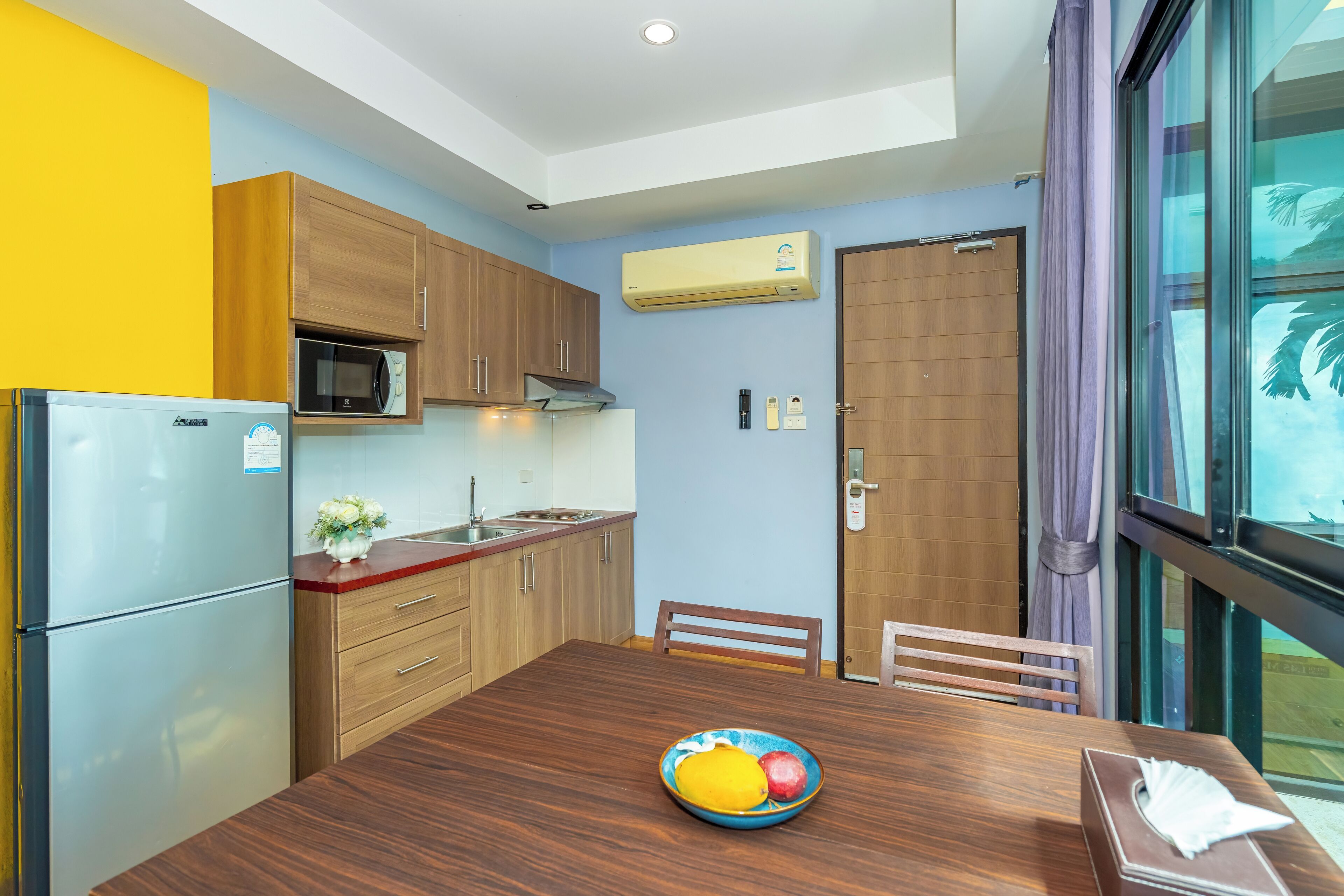 A compact kitchen with wooden cabinets, a built-in microwave, and a refrigerator.