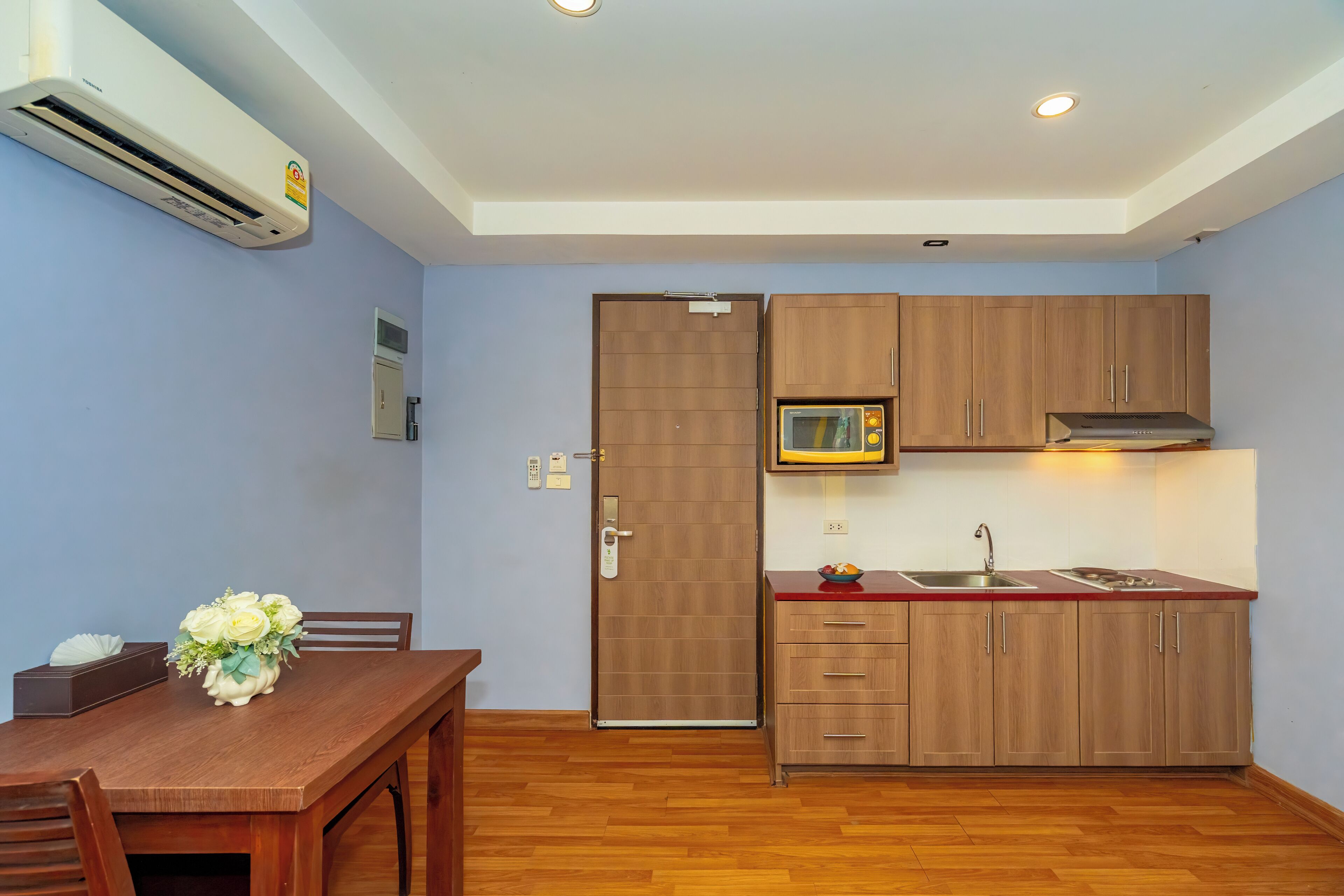 A compact kitchen with wooden cabinets, a microwave, and a sink.