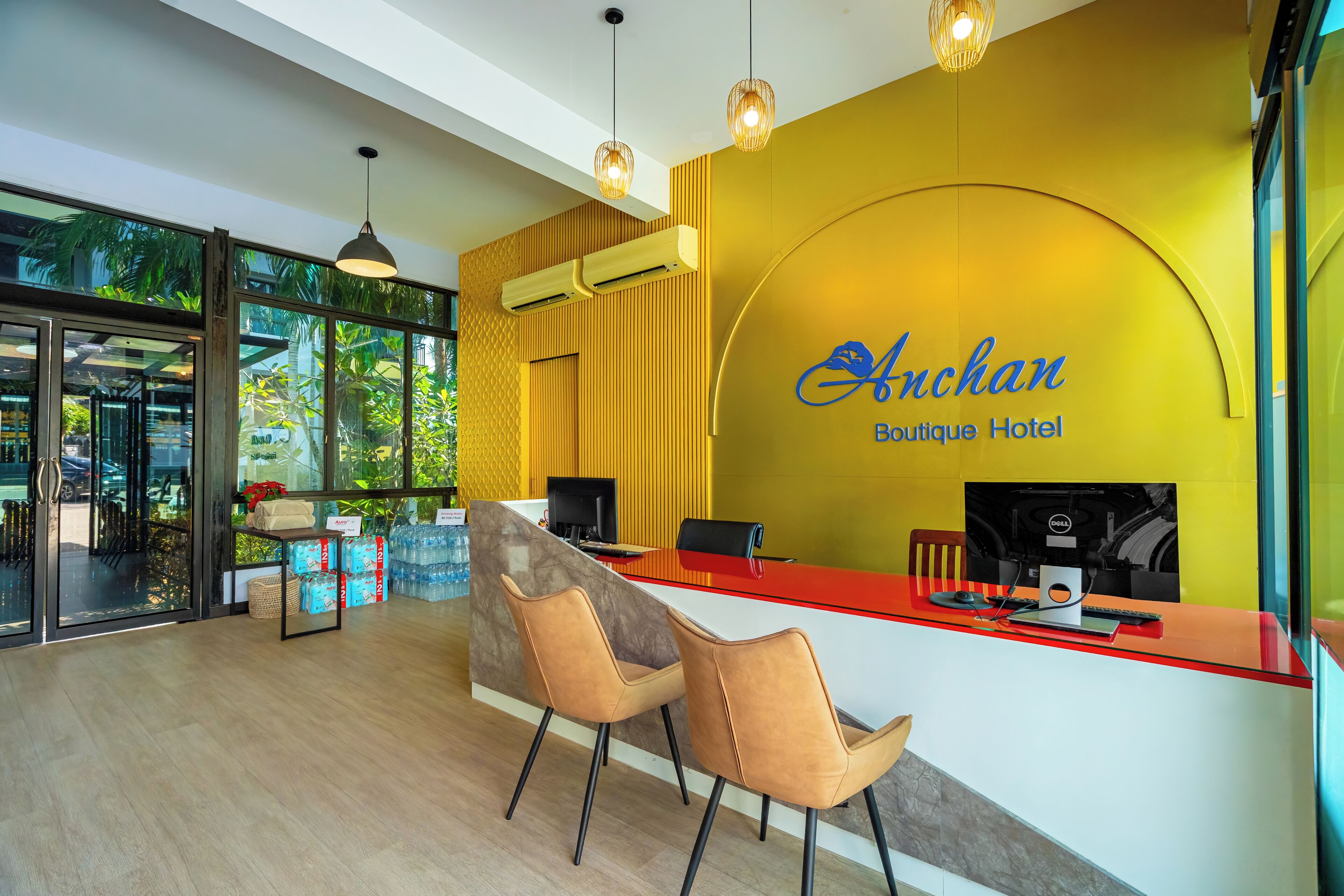A reception desk with a yellow wall and a sign that reads "Anchan Boutique Hotel".