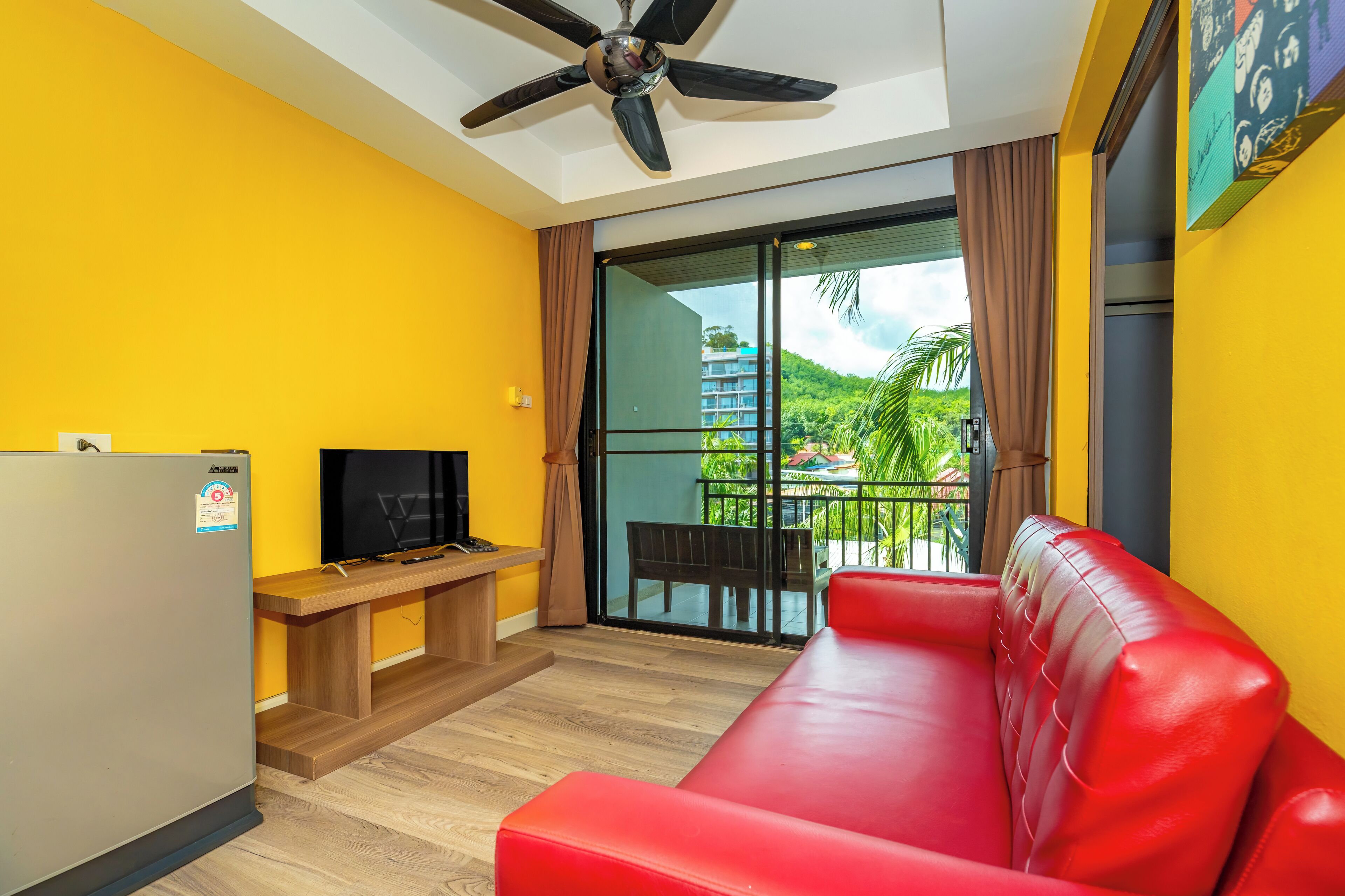 A modern living room with a red sofa, a television, and a ceiling fan.