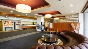 A modern lobby with a leather sofa, a glass-top coffee table, and a wooden reception desk. - Sunsky Hotel (Kitakyushu)