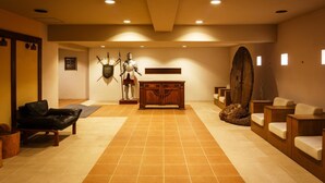 A spa area with a wooden reception desk, a statue of a knight, and a large wooden sculpture. - Sunsky Hotel (Kitakyushu)