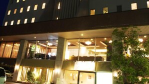 A modern hotel with a curved facade, multiple windows, and a well-lit entrance area. - Sunsky Hotel (Kitakyushu)
