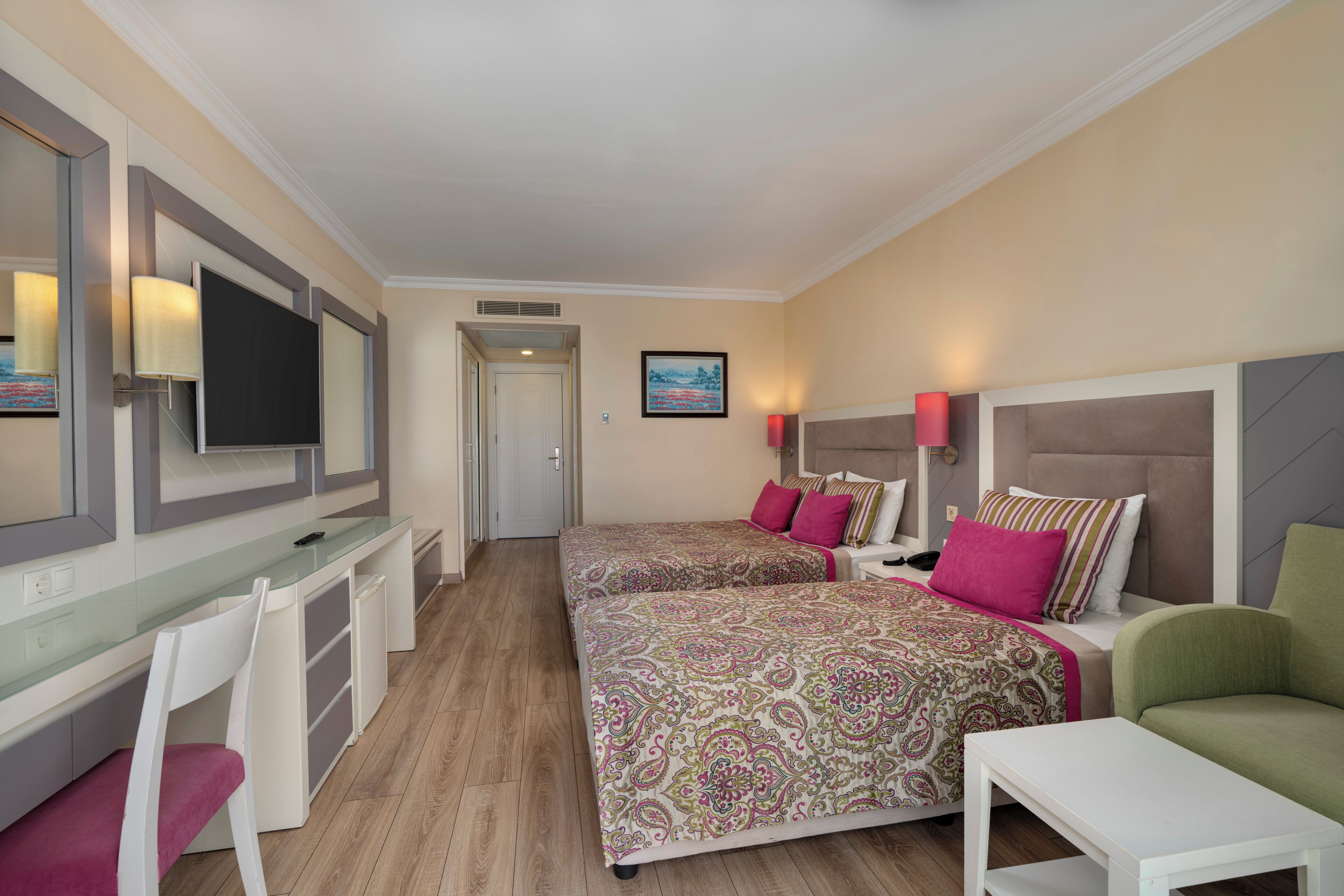 Habitación de hotel con dos camas, un escritorio, sillas y un televisor.