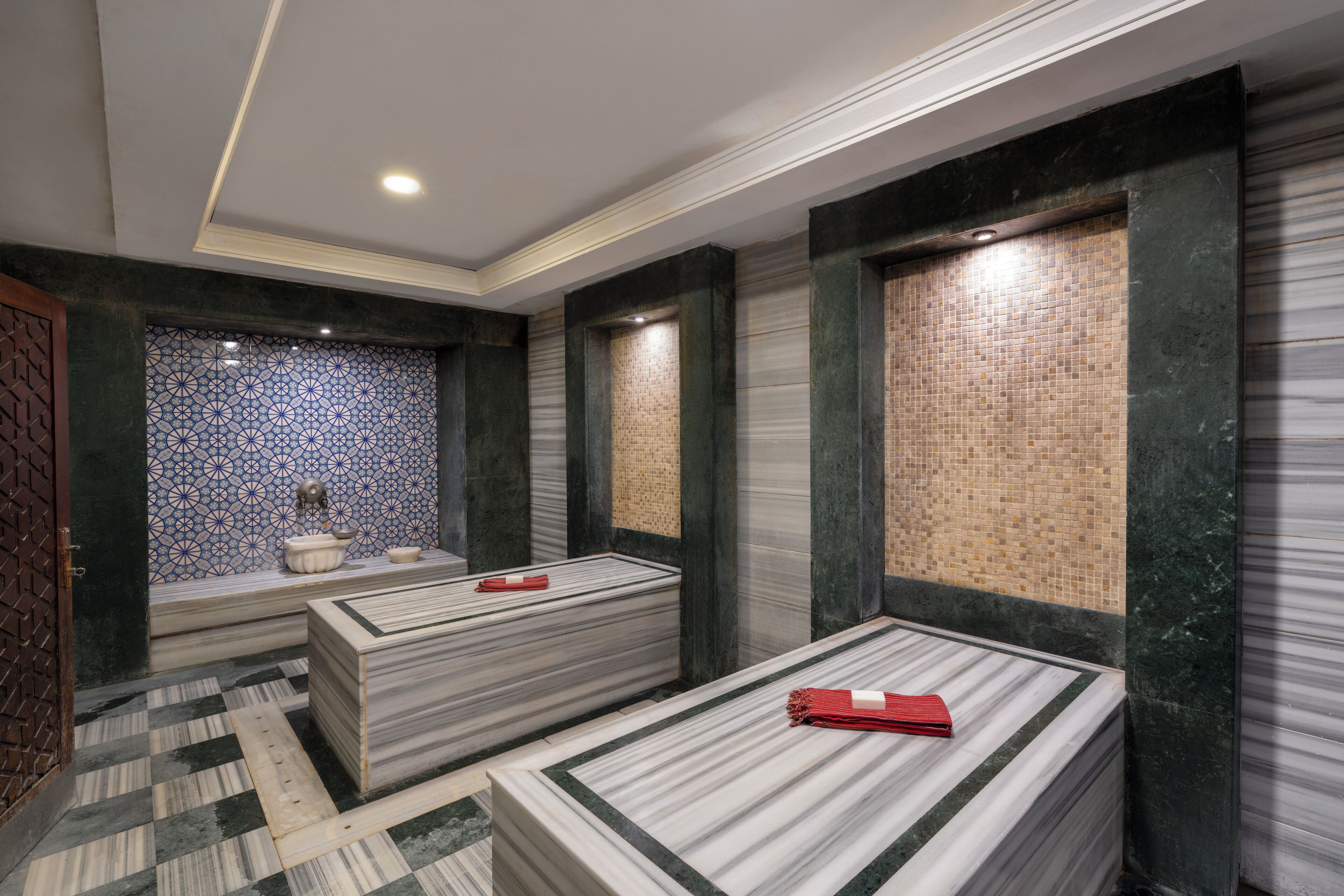 Un cuarto de spa con dos camas de tocador de mármol, una pared con diseño y un suelo a cuadros.