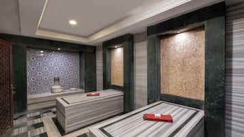 Un cuarto de spa con dos camas de tocador de mármol, una pared con diseño y un suelo a cuadros.