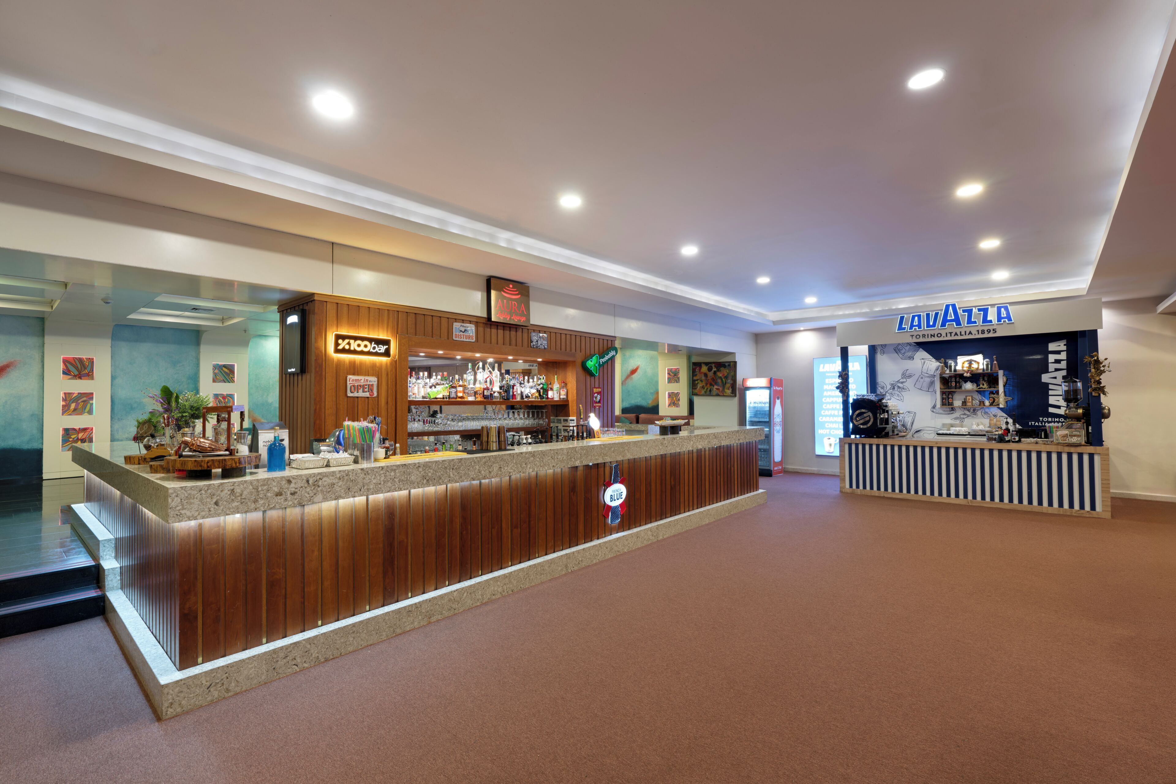 A bar area with a counter, a sign for '100bar', and a 'LAVAZZA' store in the background.