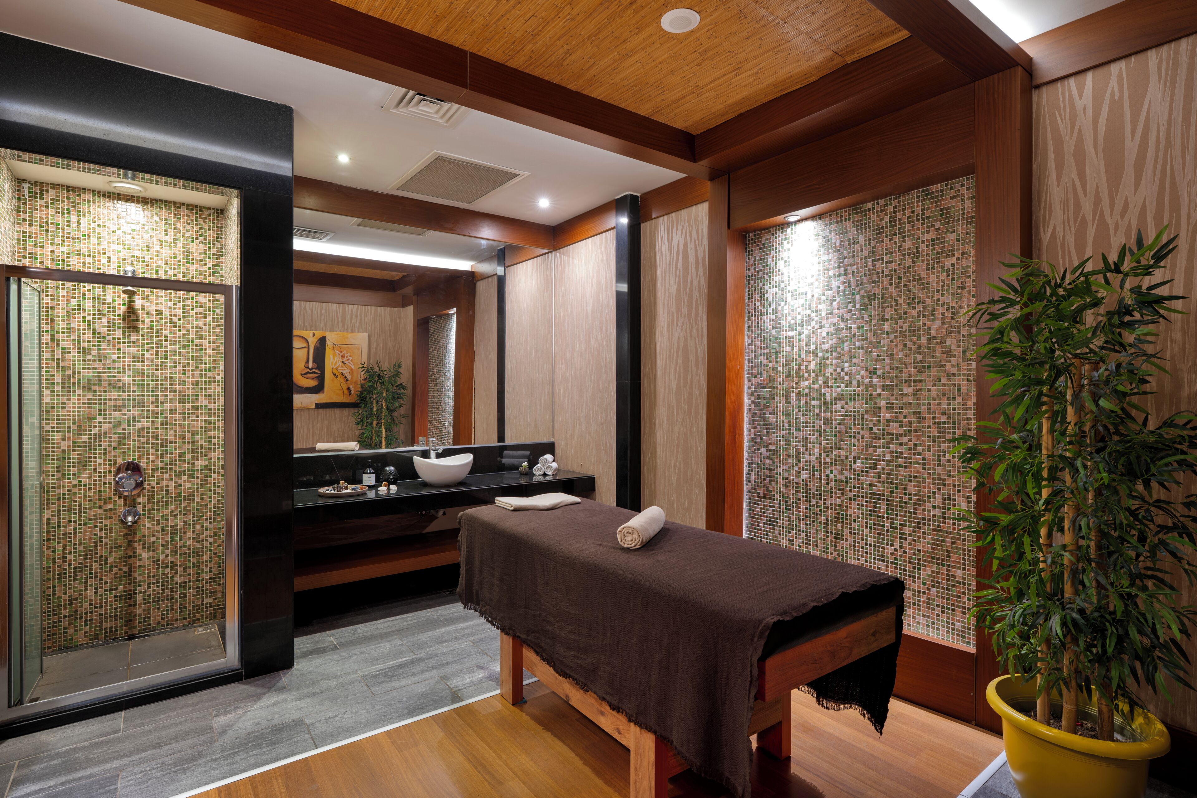 Un cuarto de spa con un banco de madera, un lavamanos, un espejo y una planta en maceta.