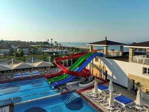Una piscina con varias toboganes, sillas de descanso y vistas al océano.