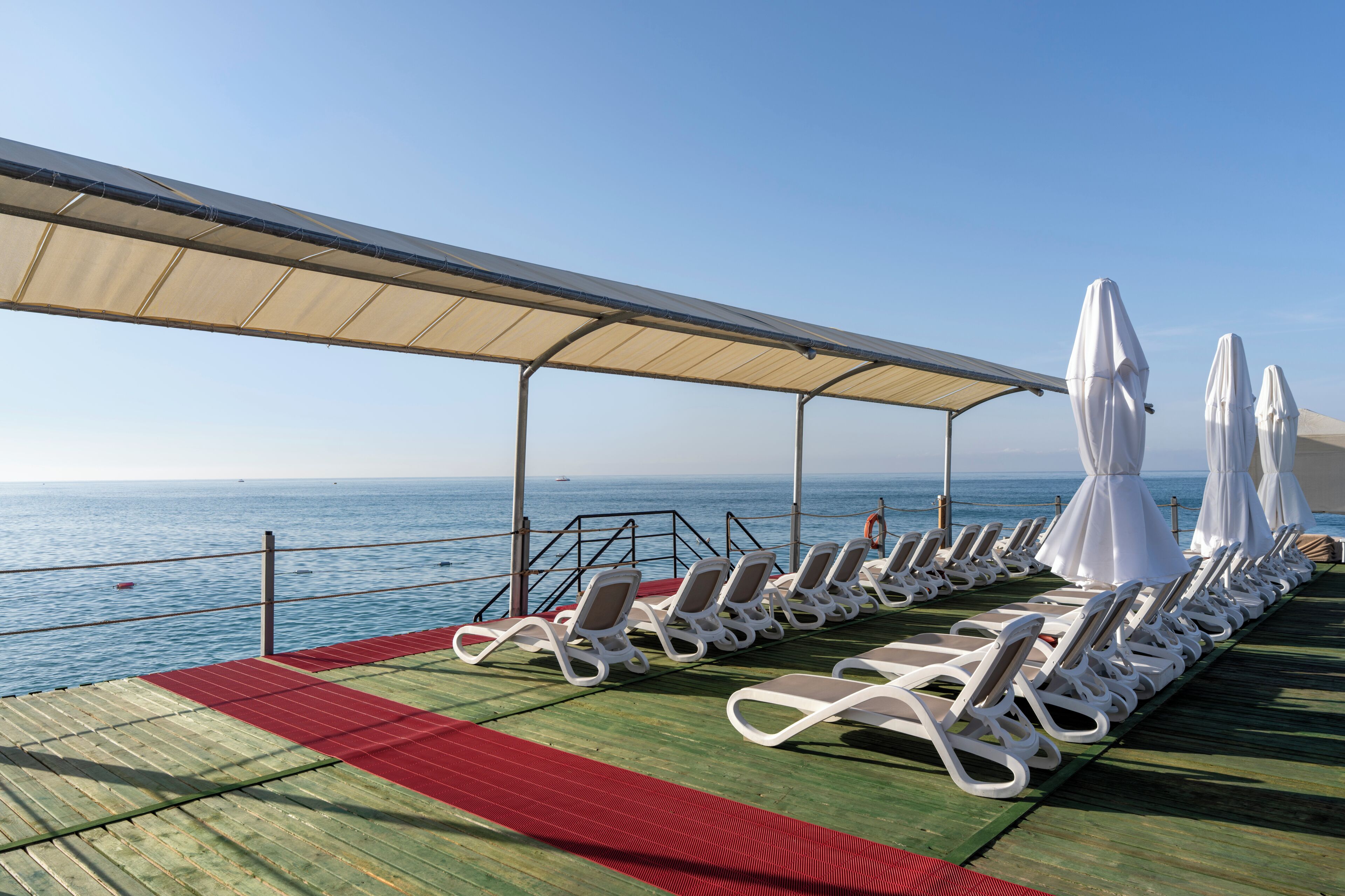 A sun deck with lounge chairs and umbrellas, overlooking the sea.
