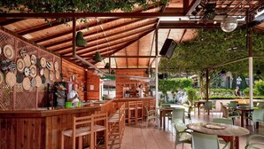 A wooden bar area with a counter, chairs, and tables. - Titan Club Hotel Ultra All Inclusive (Alanya)