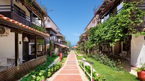 A narrow alleyway with buildings on either side, a paved walkway, and lush greenery. - Titan Club Hotel Ultra All Inclusive (Alanya)