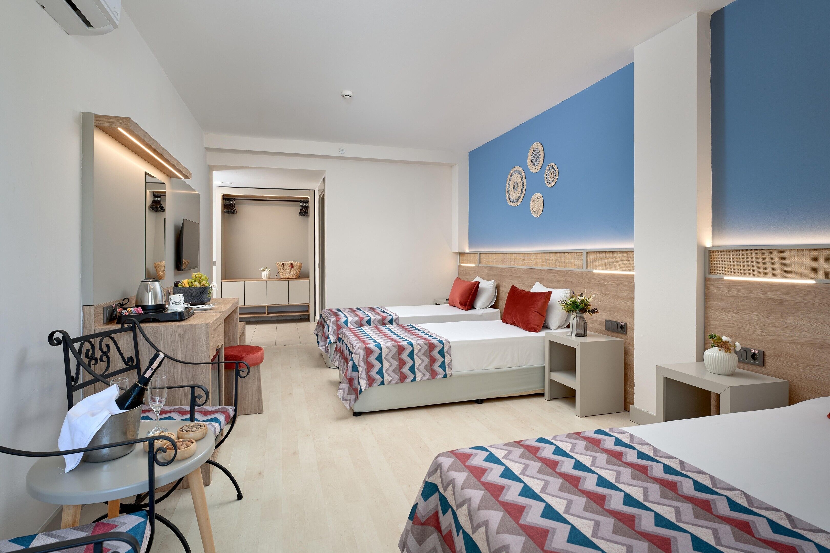 A modern hotel room with two beds, a desk, a chair, and a mirror.
