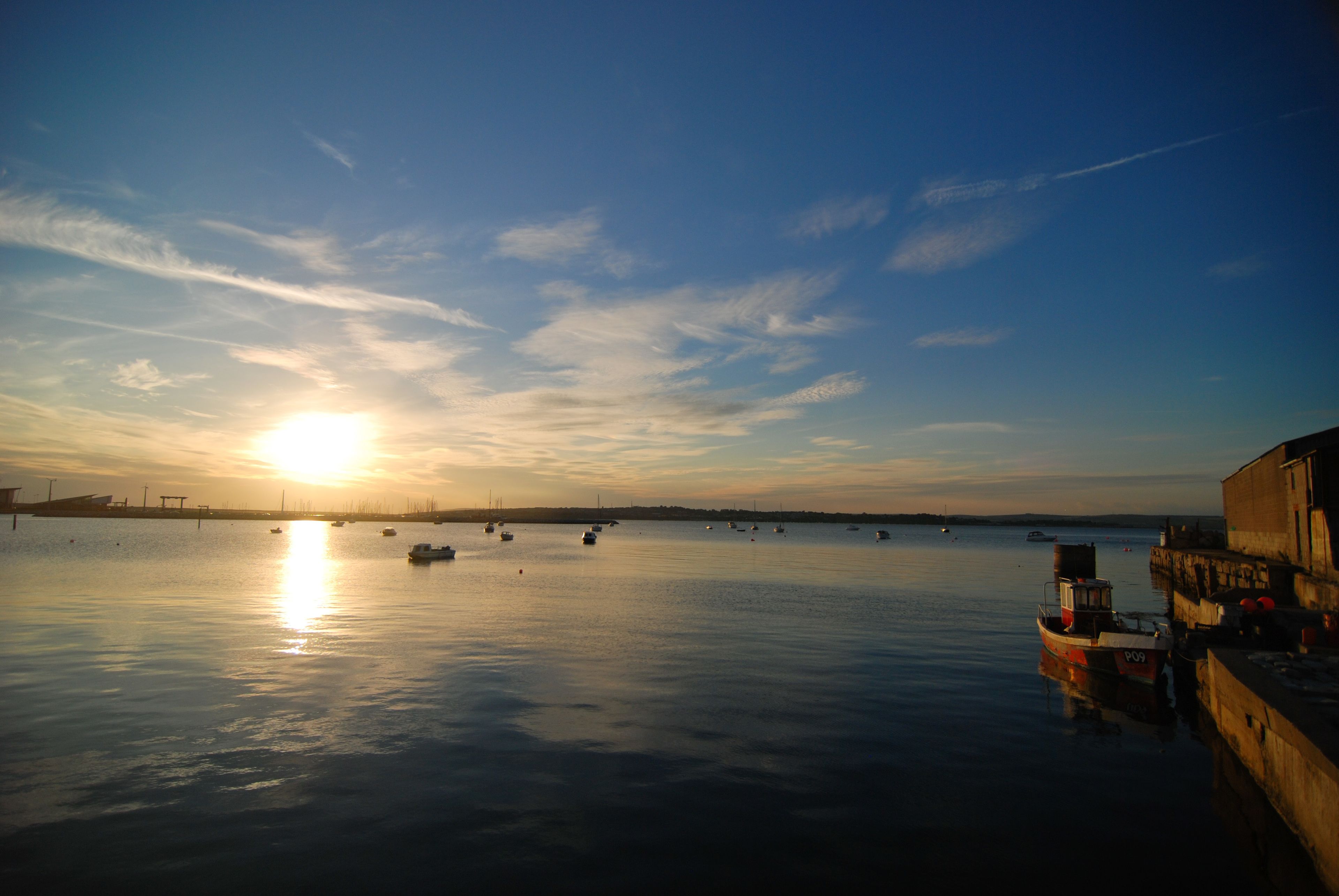 A calm waterfront with boats and a dock.