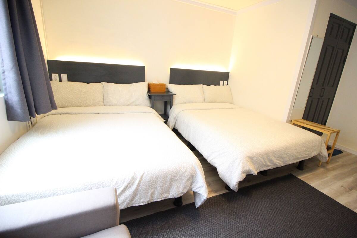 Une chambre d’hôtel avec deux lits, une table de chevet, une petite table et une porte.