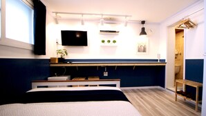 Une chambre à coucher moderne avec un lit, une table de chevet et un téléviseur fixé au mur.
