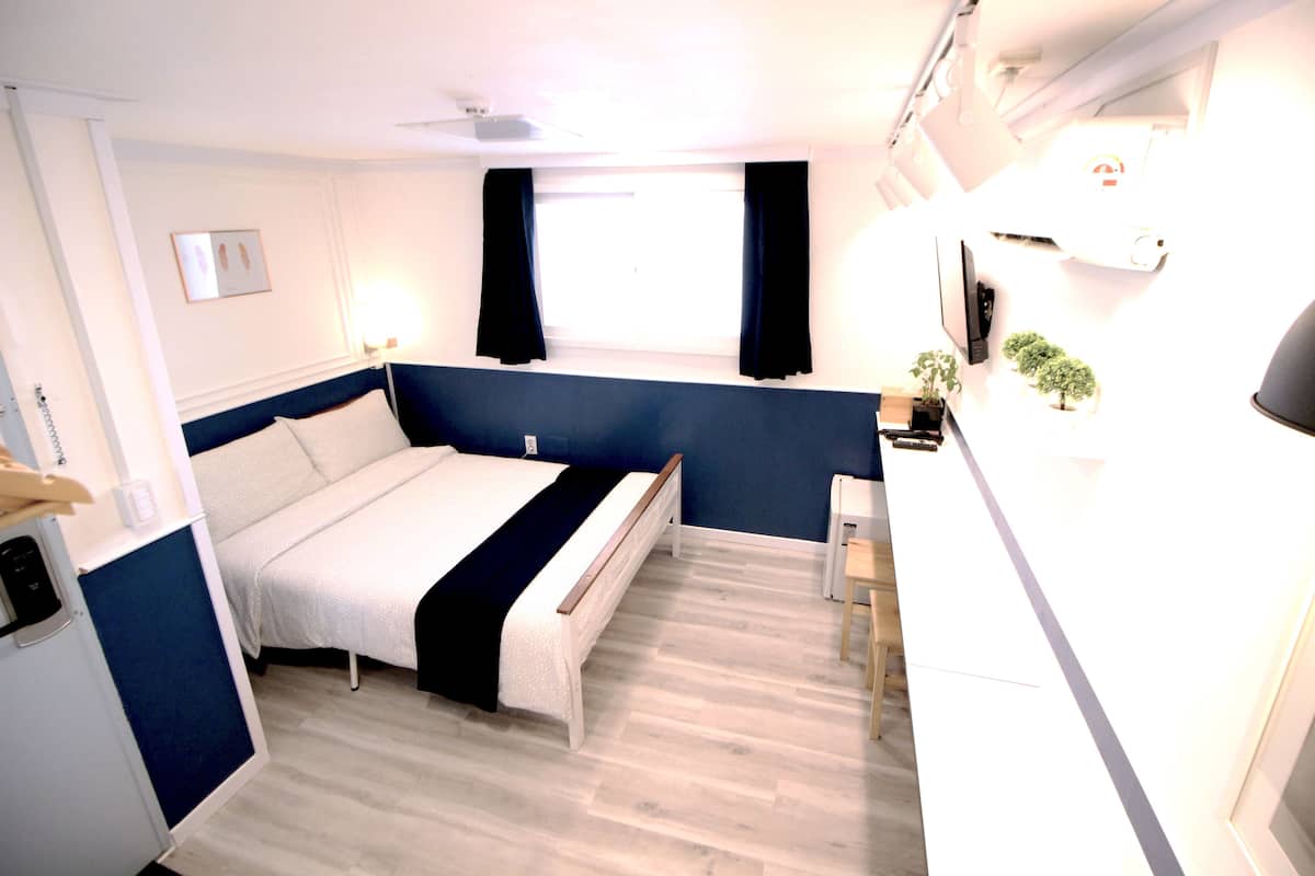 Une chambre à coucher comprenant un lit, une table de chevet et un petit bureau avec une chaise.