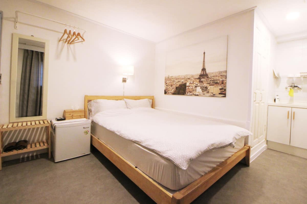 Une chambre à coucher bien rangée, avec un lit simple, une petite table de chevet, un radiateur et une armoire.