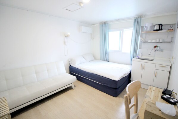 A small, clean room with a bed, a sofa, a desk, and a kitchenette. - Seoul Mansion Guest House (Seoul)