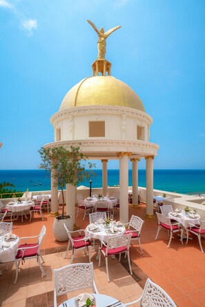 A restaurant with outdoor seating overlooking the sea, featuring a golden dome structure and white columns. - Antique Roman Palace Museum Hotel - Adults Only Ultra All Inclusive (Alanya)