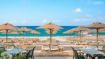 A beachside seating area with umbrellas and lounge chairs facing the ocean.