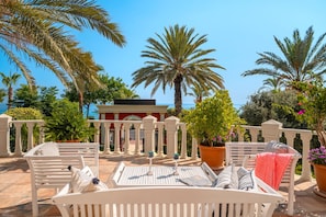 A terrace with white furniture, palm trees, and a view of the sea. - Antique Roman Palace Museum Hotel - Adults Only Ultra All Inclusive (Alanya)