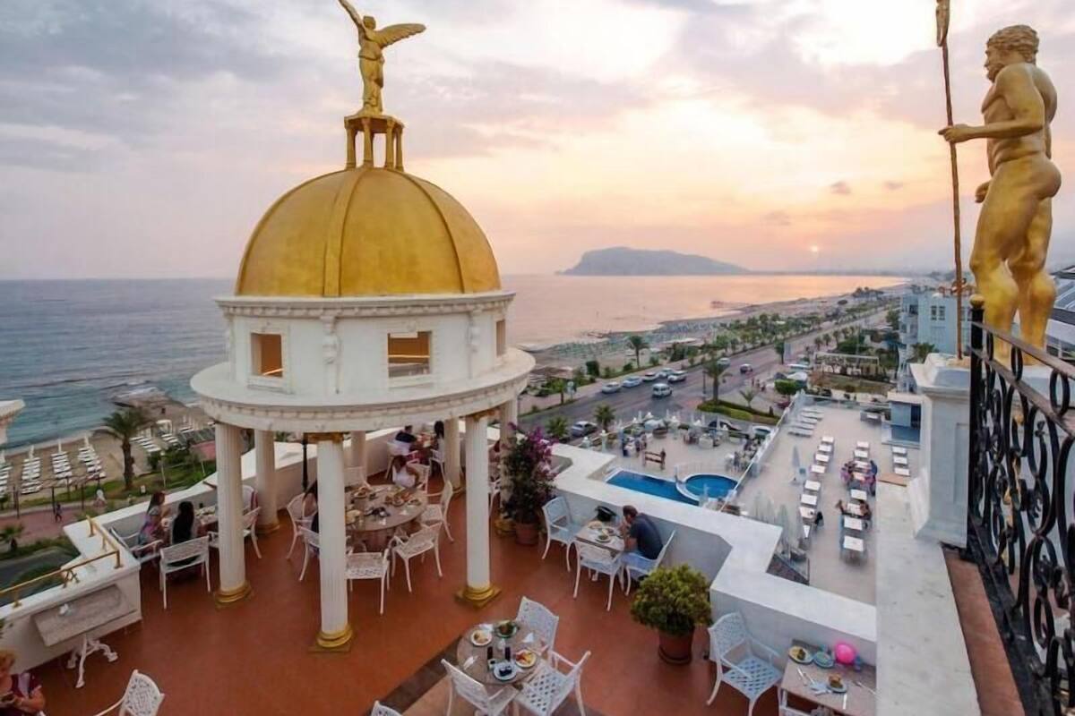 A rooftop terrace with outdoor seating, a golden dome structure, and a statue.