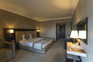 Una habitación de hotel con cama, mesitas de noche, escritorio, silla y espejo.