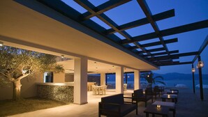 Un espace extérieur aménagé pour les repas, avec des tables et des chaises, une pergola et une vue sur la mer.
