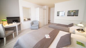 A hotel room with two beds, a desk with a TV, a chair, and a wardrobe. - Hotel Toskana (Wiesbaden)