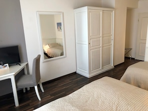 Een slaapkamer met een bed, een bureau met stoel, een kledingkast en een spiegel.