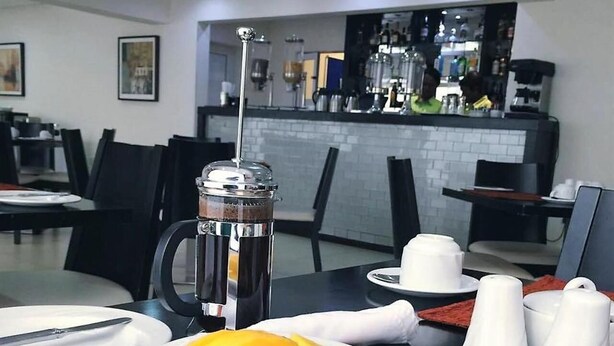 Ein Frühstückstisch mit Eiern, Obst und Gebäck, eine Kaffeemaschine und eine Bar im Hintergrund.