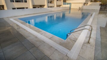 Una piscina al aire libre, sombrillas, sillones reclinables de piscina