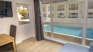 Ein Zimmer mit großem Fenster und Blick auf einen Swimmingpool, einem Holztisch und einem blauen Sofa.