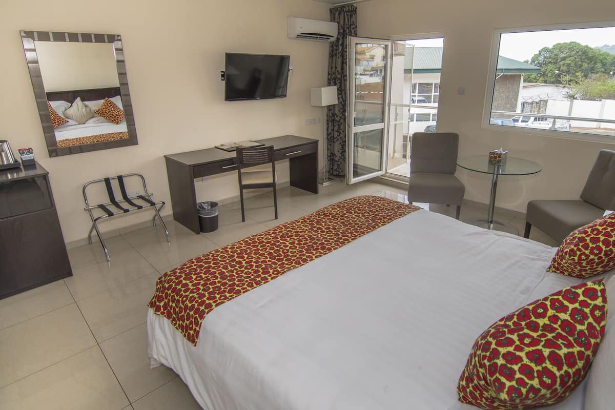 A hotel room with a bed, desk, chair, and a TV.