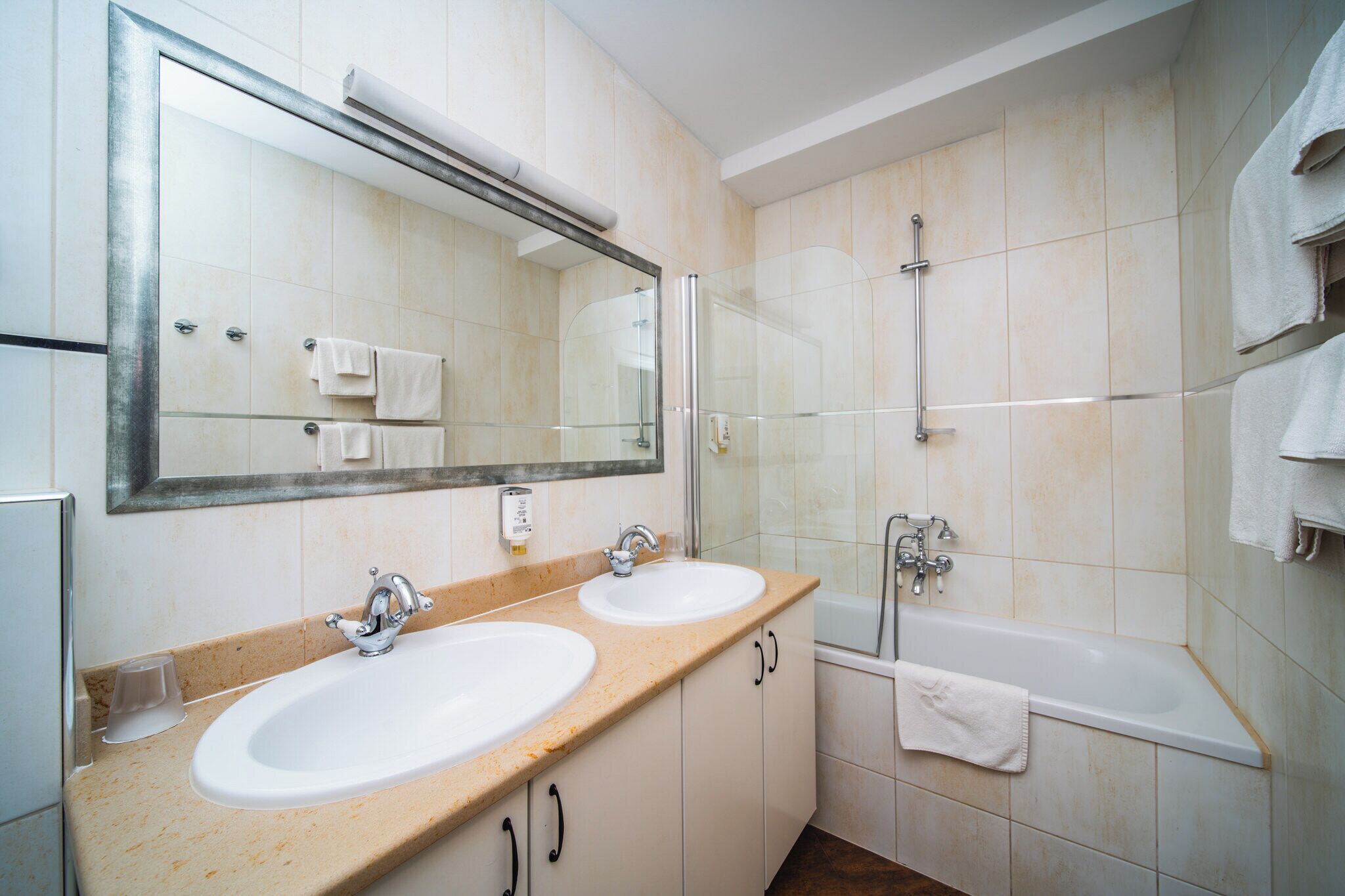 Un baño con dos lavamanos, un espejo grande, cabina de ducha de vidrio y una bañera.