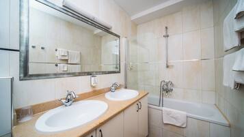 Un baño con dos lavamanos, un espejo grande, cabina de ducha de vidrio y una bañera.