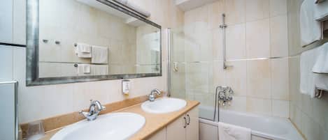 A bathroom with two sinks, a large mirror, a glass shower enclosure, and a bathtub.