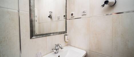 A bathroom with a sink, mirror, and towel dispenser.