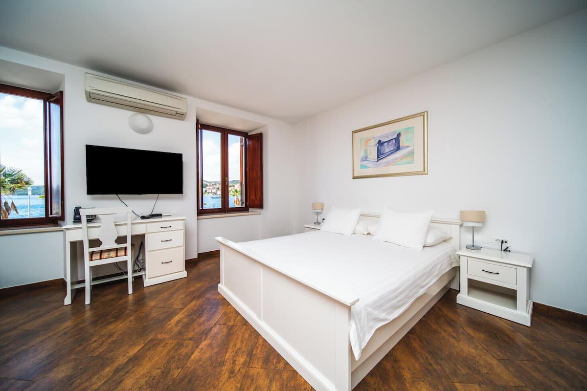 A bedroom with a bed, a desk, and a TV.