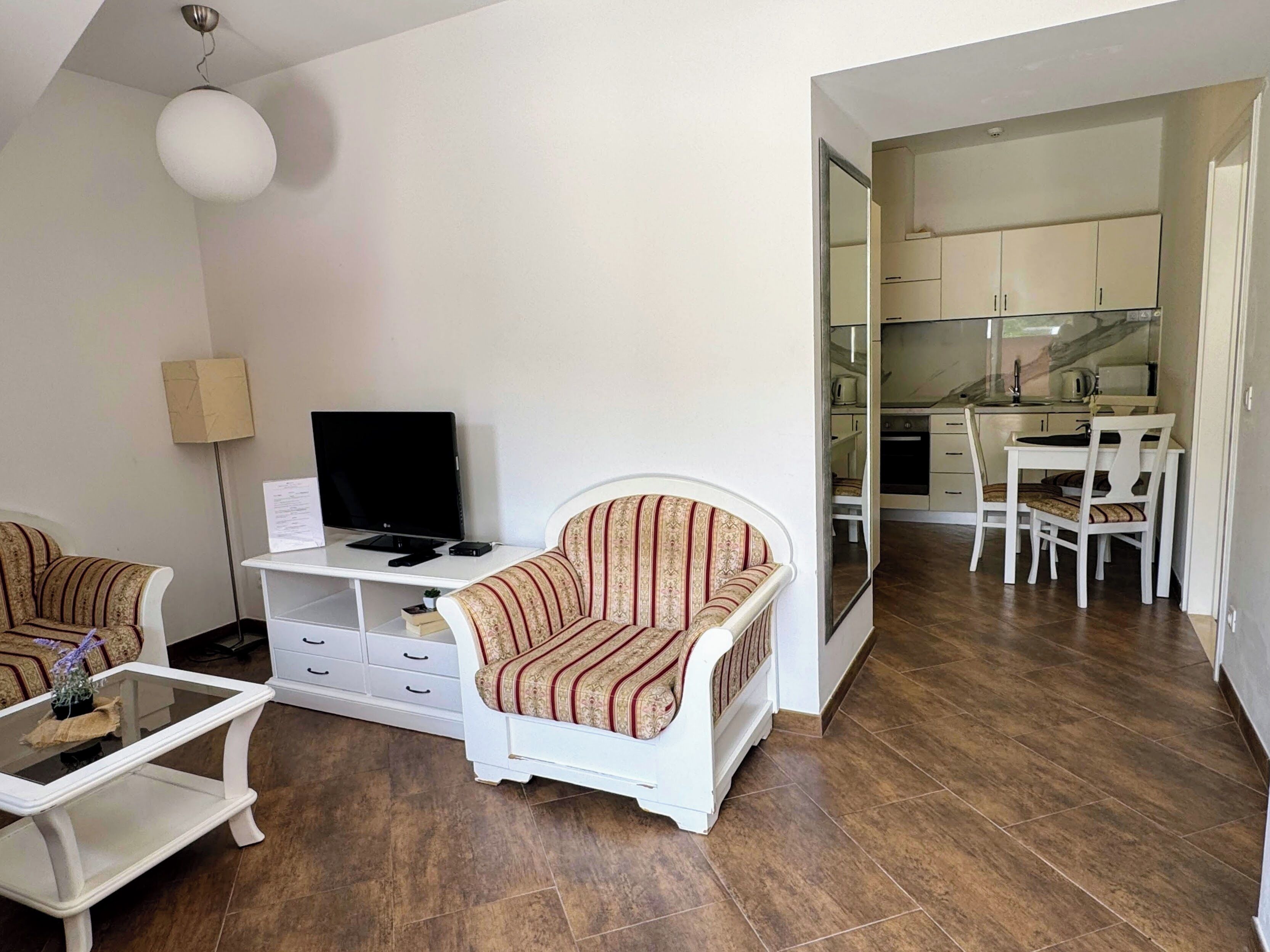 A living room with a sofa, a coffee table, a TV, and a dining area with chairs and a table.