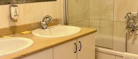 A bathroom with two sinks, a mirror, a glass shower enclosure, and a bathtub.