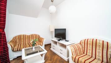 Una sala de estar con dos sofás, una mesa de centro, un televisor y una lámpara.