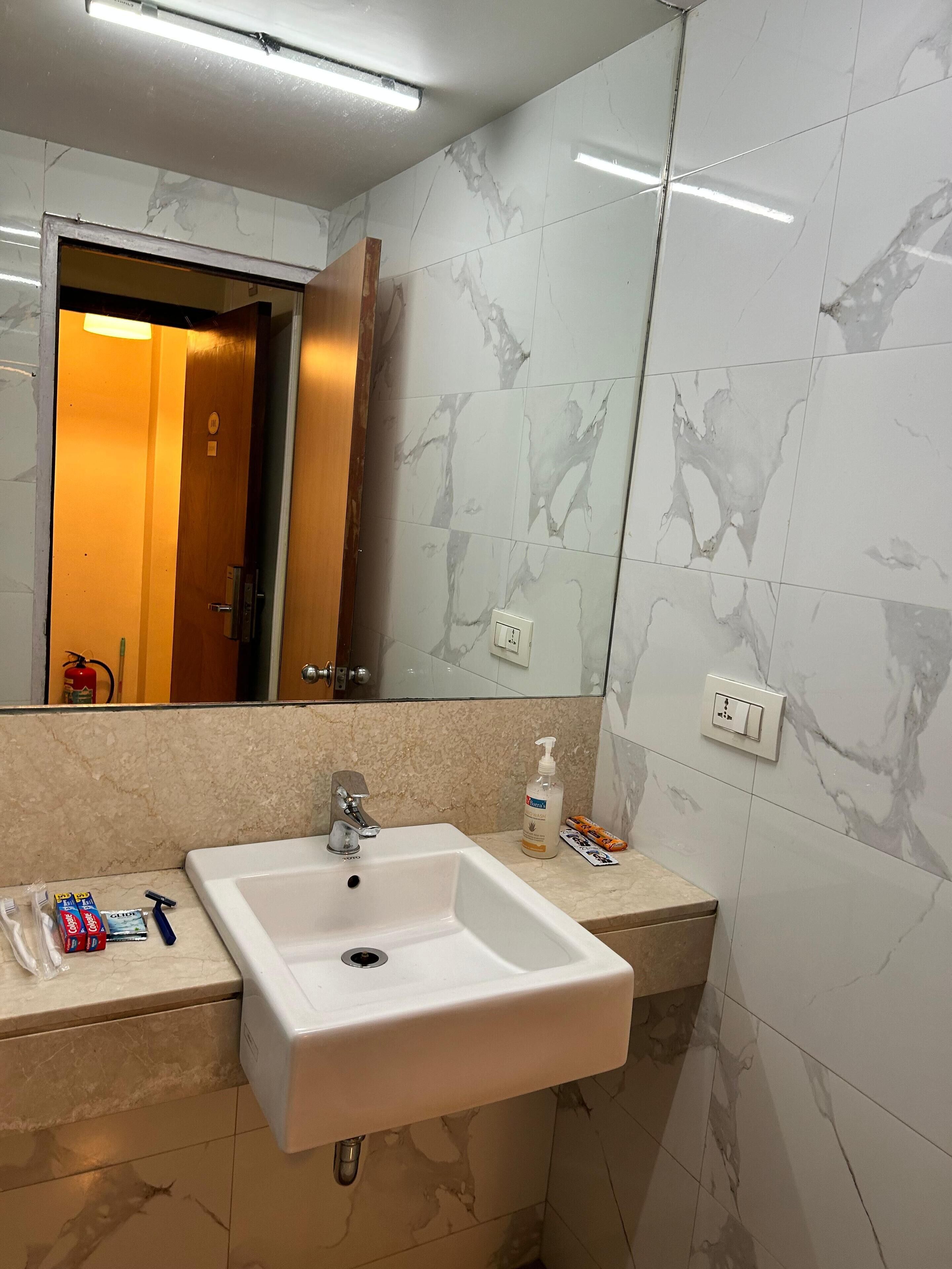 A bathroom with a white sink, a mirror, and marble walls.