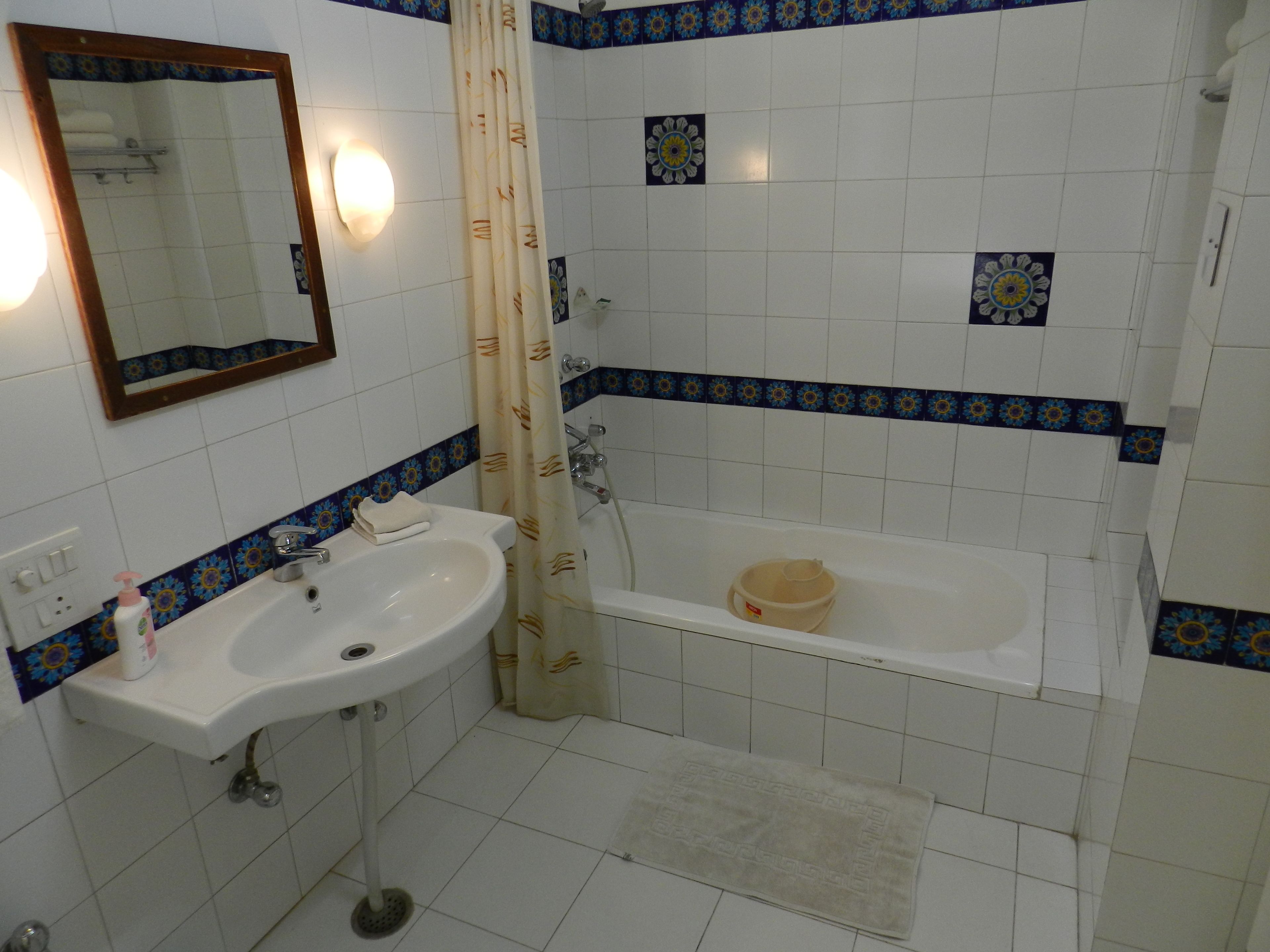 A bathroom with a sink, mirror, and bathtub.