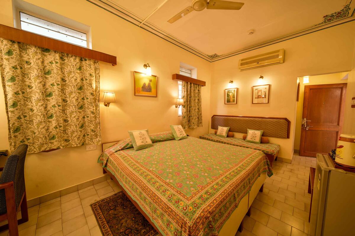 Un dormitorio con una cama grande, dos mesitas de noche, un ventilador de techo y una puerta.