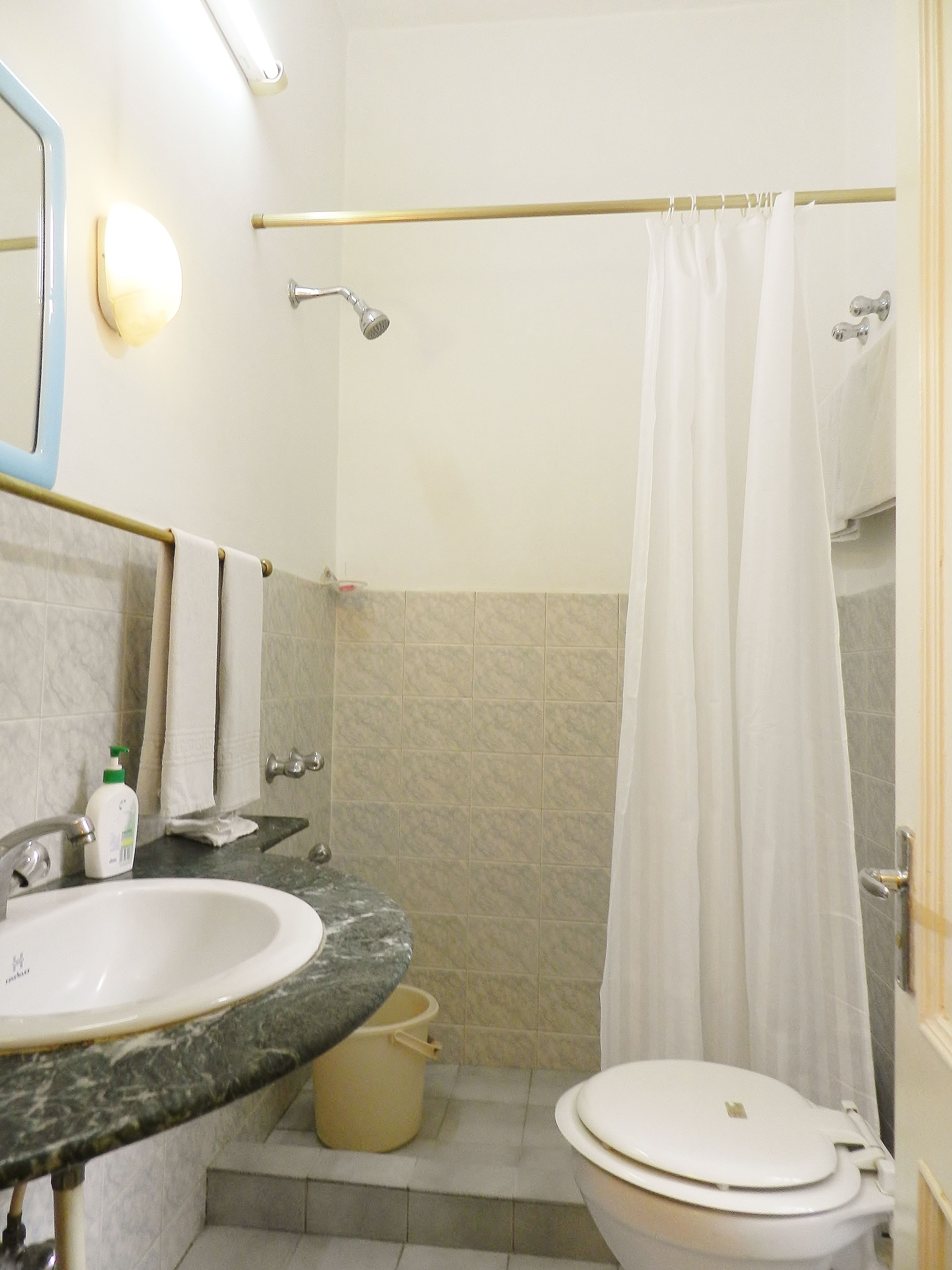 A bathroom with a sink, mirror, toilet, and shower curtain.