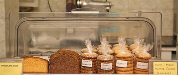Egy pékség kirakata, amelyben különféle sütemények találhatók, köztük csokoládétorta, csokoládés kesudiós keksz és kókuszos keksz.