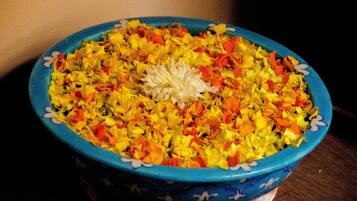 A bowl of colorful flower petals with a white flower in the center, placed on a table.