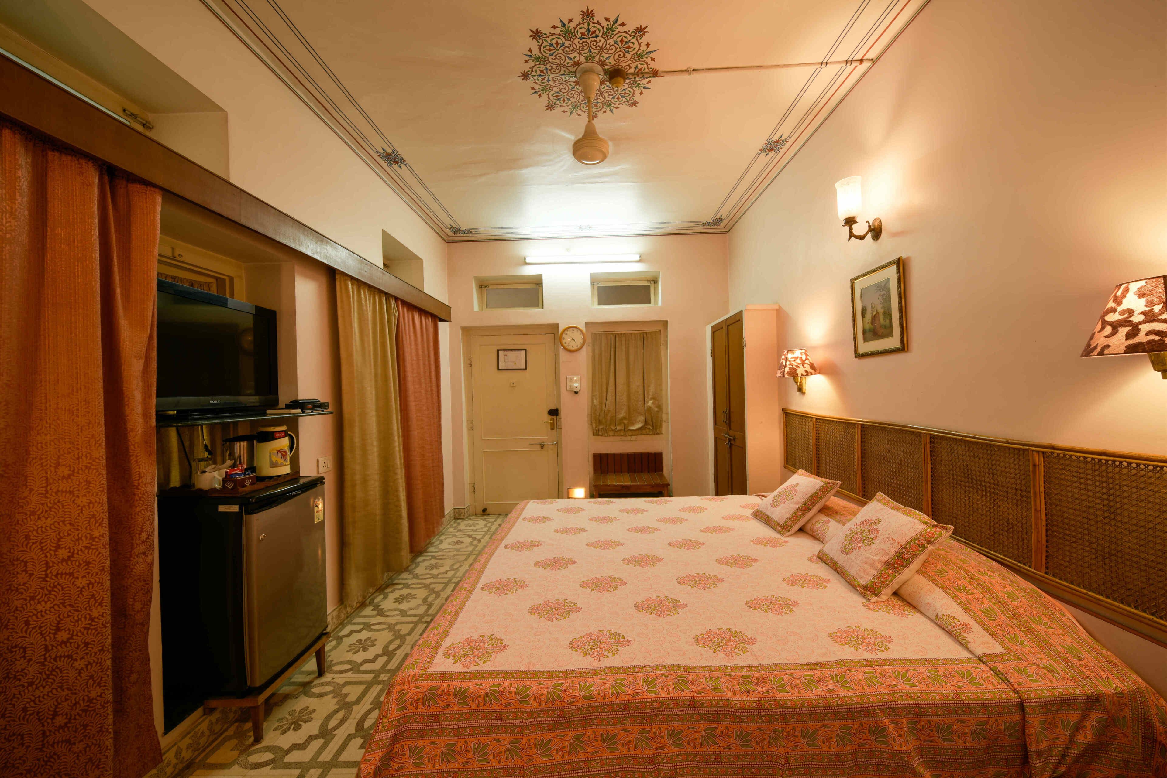 A hotel room with a bed, a television, a desk, and a wardrobe.